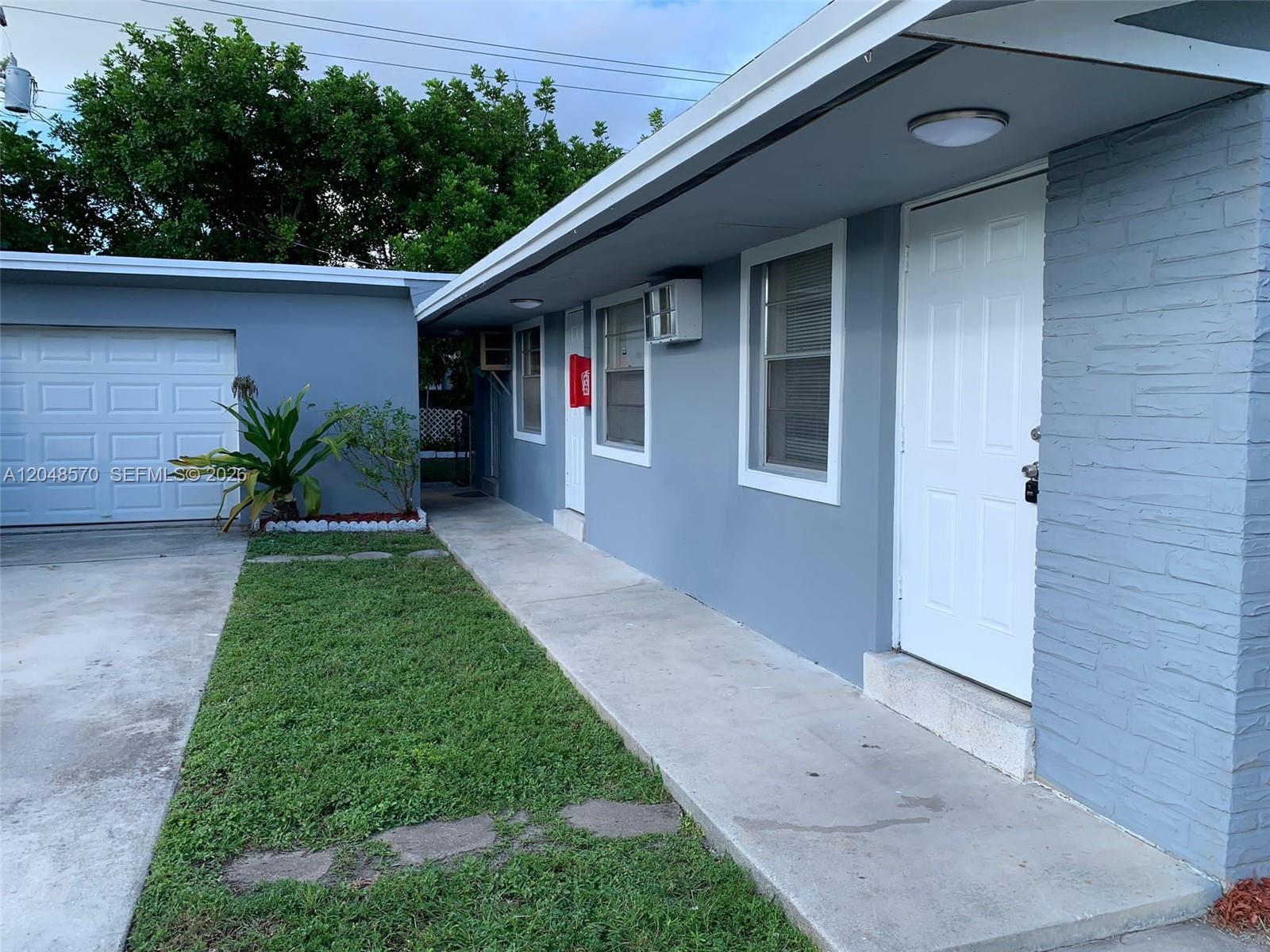 A gray house exterior features a white door, a walkway, and a garage — 6317 SW 18th St # 1, Miramar FL 33023, MIRAMAR, FL