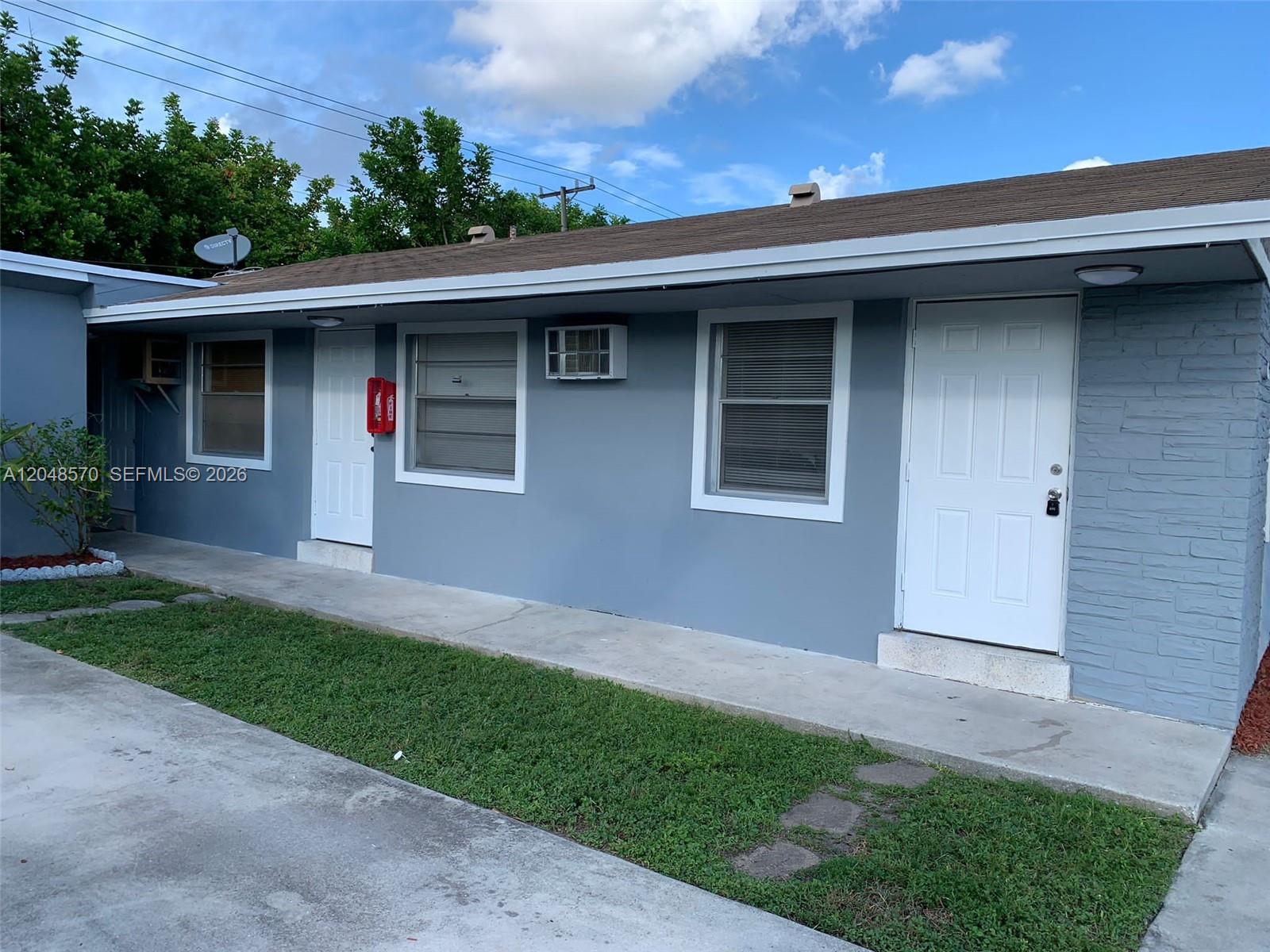A single-story blue building features two white doors, two windows, and a concrete walkway — 6317 SW 18th St # 1, Miramar FL 33023, MIRAMAR, FL
