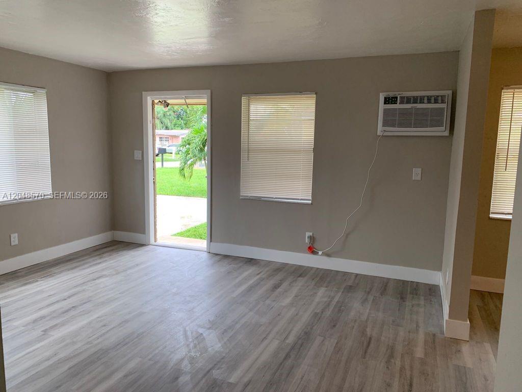 This room features light wood-look flooring, beige walls, a window air conditioner, and a doorway — 6317 SW 18th St # 1, Miramar FL 33023, MIRAMAR, FL