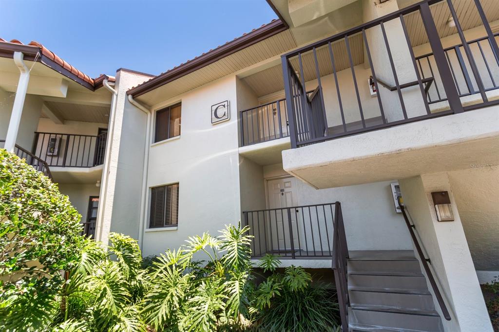 Exterior view of a two-story apartment building with a staircase leading to a second-floor entrance — 1515 PINELLAS BAYWAY UNIT C31, TIERRA VERDE, FL