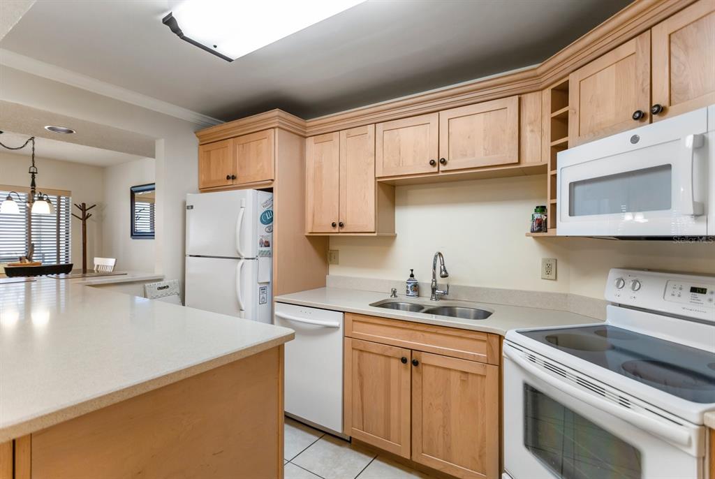 A kitchen with light wood cabinets, white appliances, and a peninsula countertop — 1515 PINELLAS BAYWAY UNIT C31, TIERRA VERDE, FL