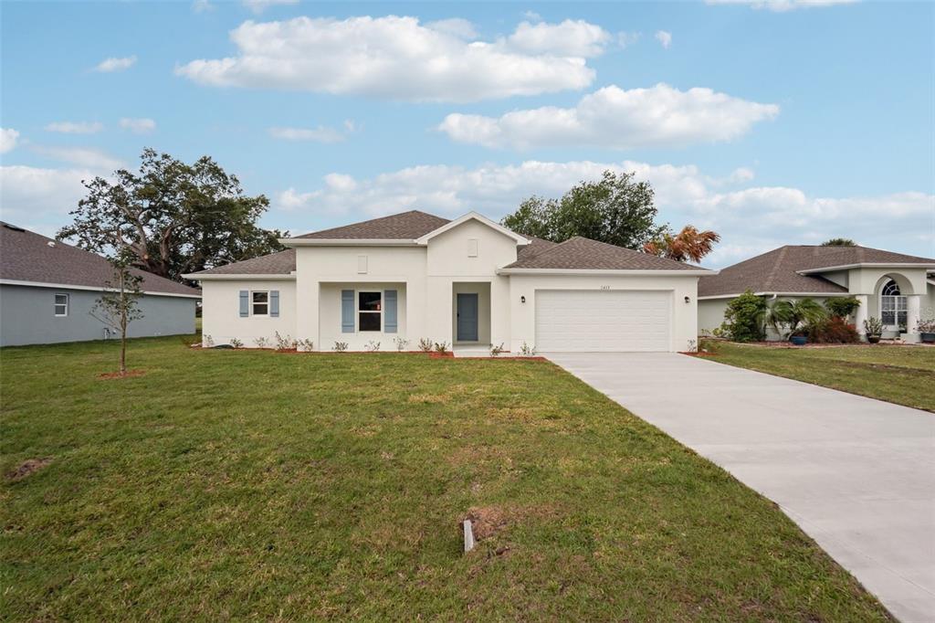 A single-story white stucco house with a two-car garage and a concrete driveway — 12025 PENGUIN AVENUE, WEEKI WACHEE, FL