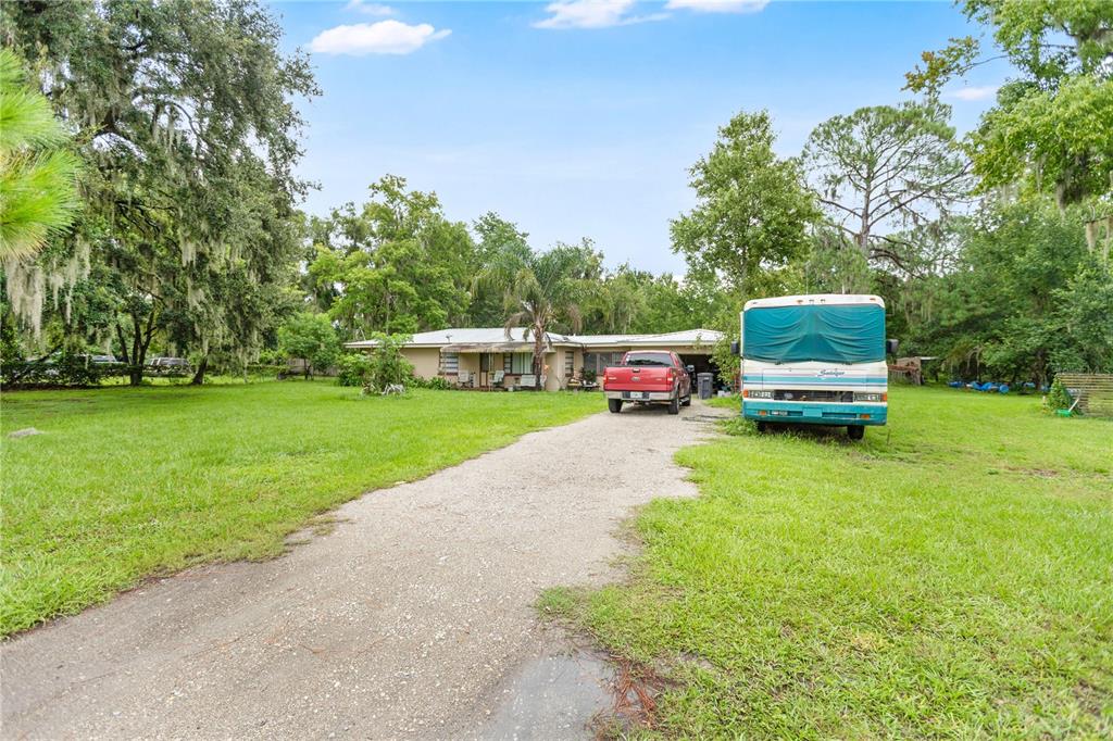 A single-story house with a gravel driveway, a red pickup truck, and a parked RV — 3702 CORK ROAD, PLANT CITY, FL