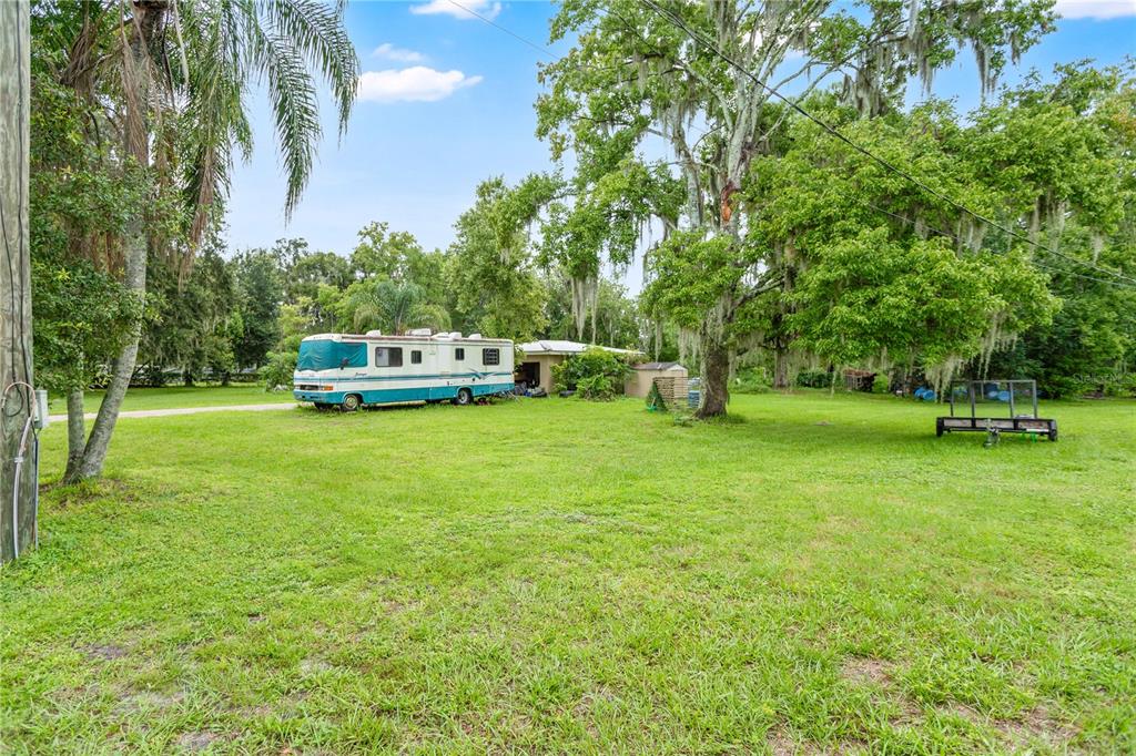 A large grassy yard features a parked motorhome, a small shed, and mature oak trees — 3702 CORK ROAD, PLANT CITY, FL