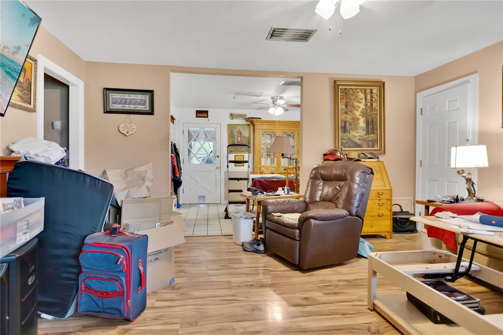 A living room with wood-look flooring, a brown recliner, and an open doorway to a dining area — 3702 CORK ROAD, PLANT CITY, FL