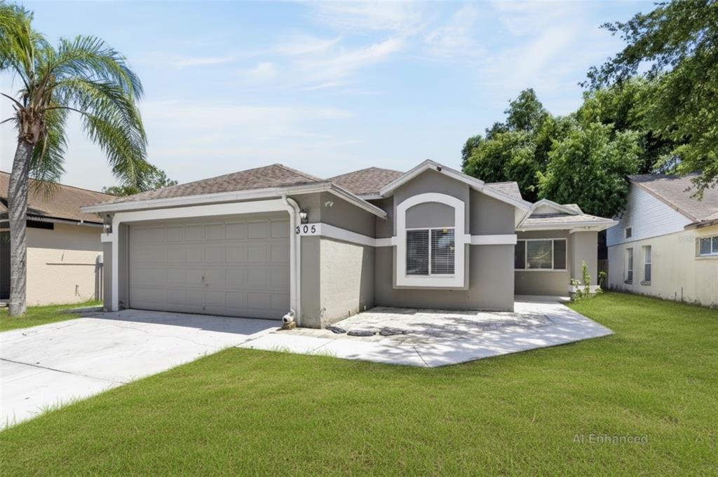 A single-story gray house with a two-car garage and a paved front patio — 305 SAND RIDGE DRIVE, VALRICO, FL