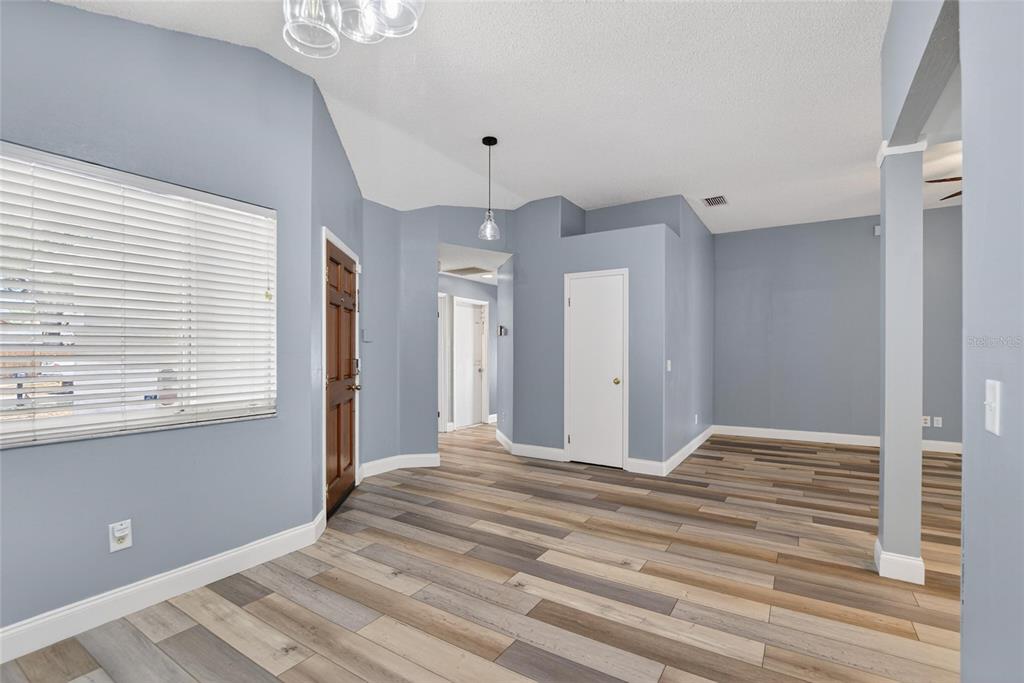 An empty room with blue walls, wood-look flooring, a brown door, and white trim — 305 SAND RIDGE DRIVE, VALRICO, FL