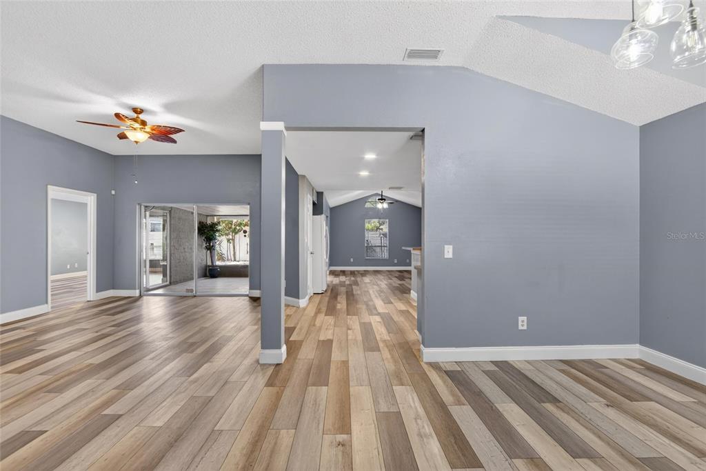 An open-concept living area features gray walls, wood-look flooring, and a vaulted ceiling — 305 SAND RIDGE DRIVE, VALRICO, FL