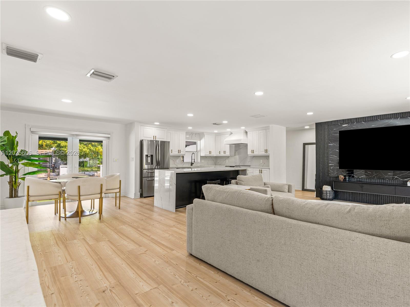 A modern open-concept living room and kitchen featuring light wood floors and a black accent wall — 1701 SW 3rd Ave, Pompano Beach FL 33060, POMPANO BEACH, FL