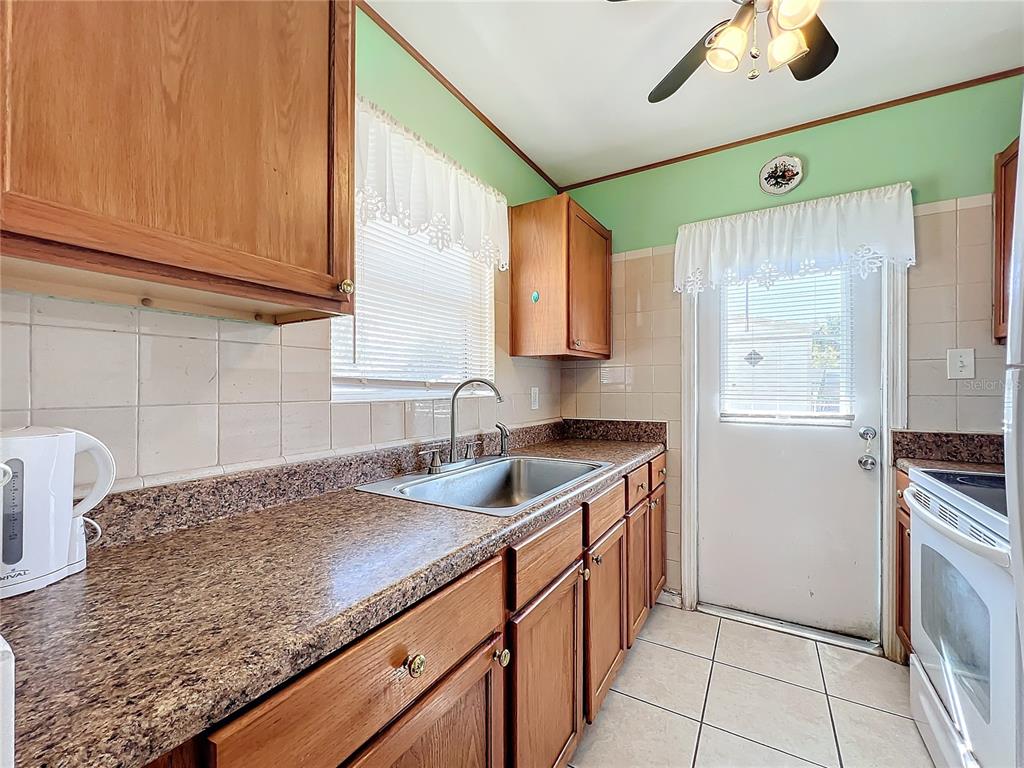 A kitchen features wood cabinets, granite-look countertops, a stainless steel sink, and light tile flooring — 8333 HERBISON AVENUE, NORTH PORT, FL