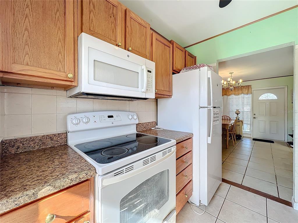A kitchen features wood cabinets, a white stove, a microwave, and a white refrigerator — 8333 HERBISON AVENUE, NORTH PORT, FL