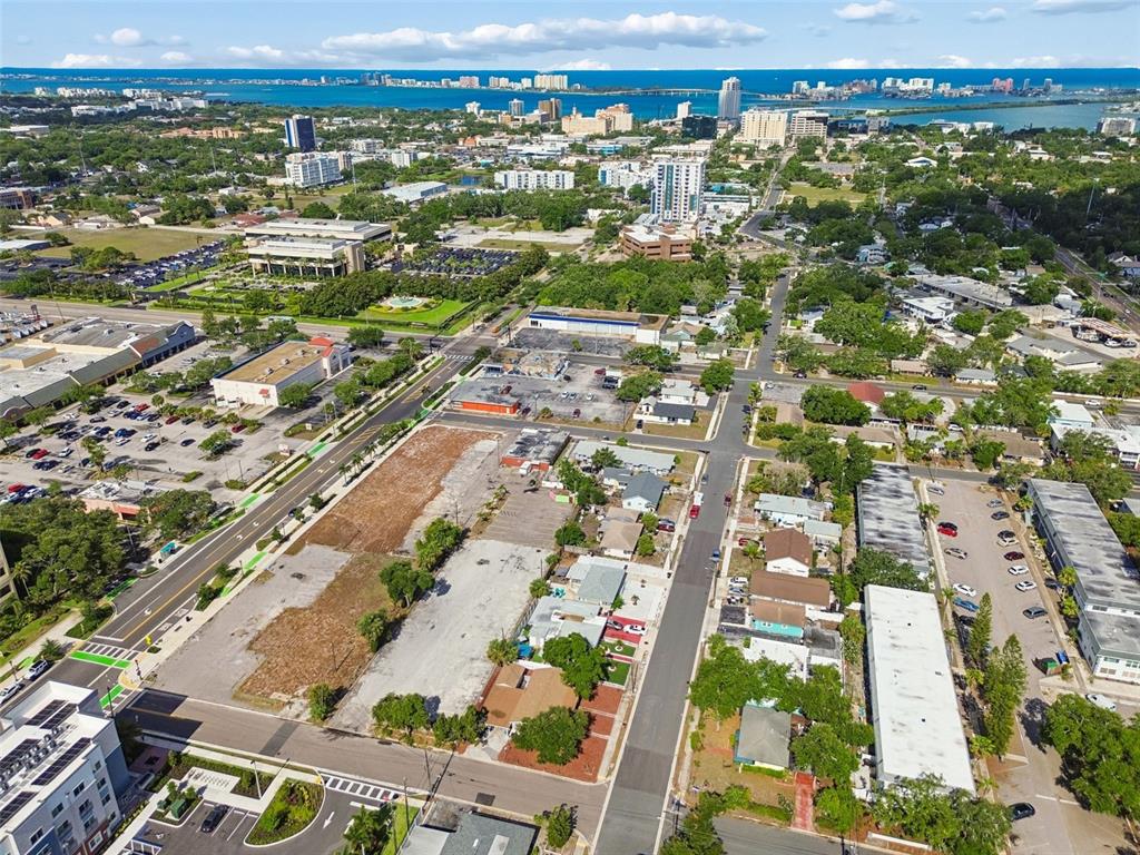 An aerial view shows a vacant lot in a city with surrounding buildings and roads — 1214-1242 CLEVELAND STREET, CLEARWATER, FL