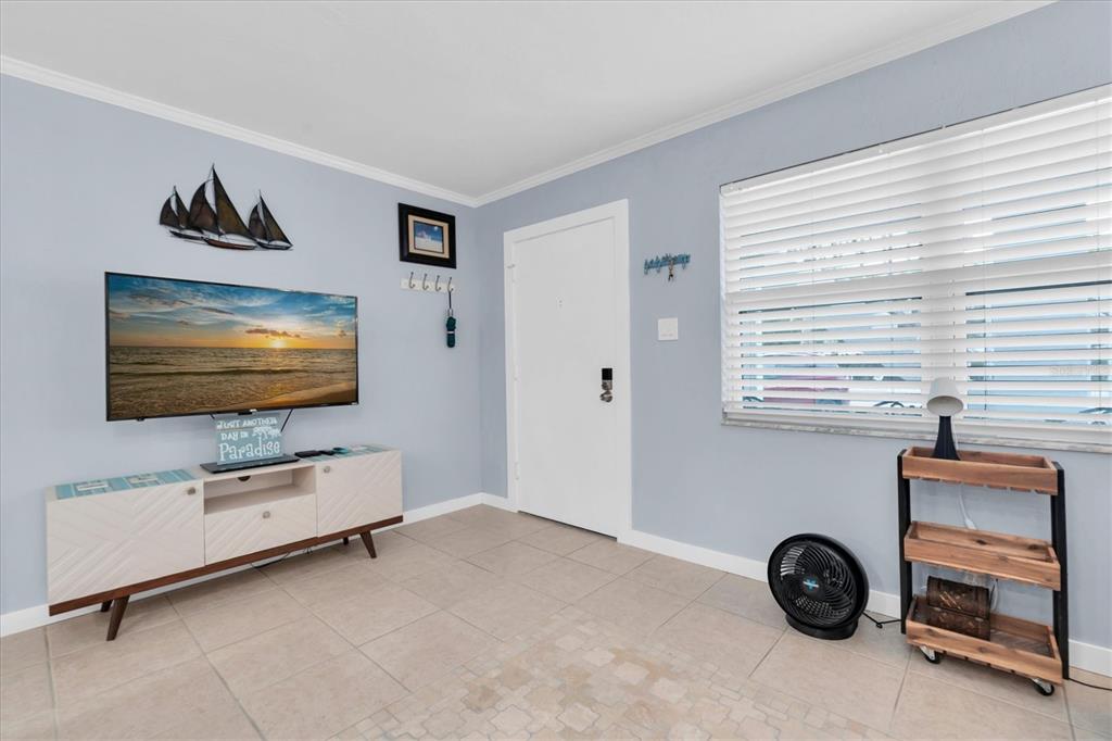 A living room features light blue walls, tile flooring, a television console, and a window — 8800 BLIND PASS ROAD UNIT 4, ST PETE BEACH, FL