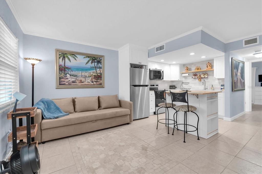A studio apartment featuring a sofa, kitchen area with a breakfast bar, and tile flooring — 8800 BLIND PASS ROAD UNIT 4, ST PETE BEACH, FL