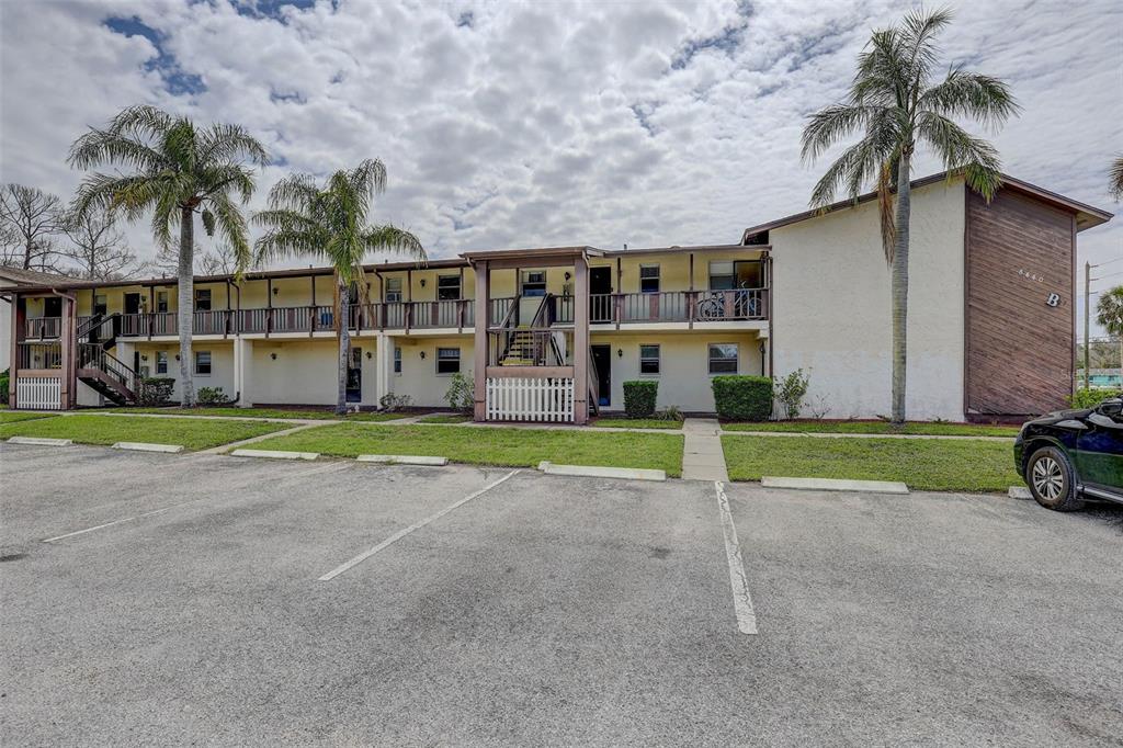 A two-story apartment building with a parking lot in front and palm trees — 8440 OLD POST ROAD UNIT 104, PORT RICHEY, FL