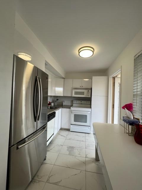 A kitchen features stainless steel appliances, white cabinetry, and light-colored tile flooring — 3001 S Course Drive # 403, Pompano Beach FL 33069, POMPANO BEACH, FL