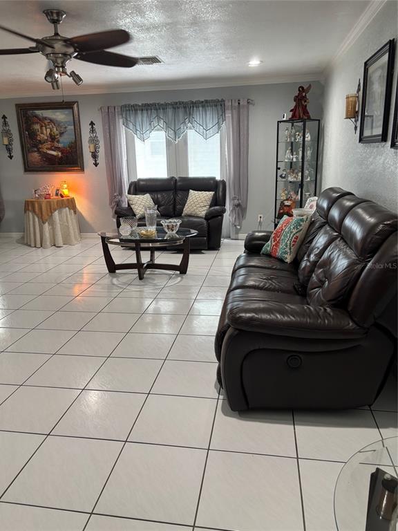 A living room features white tile flooring, two dark leather sofas, and a ceiling fan — 5450 GAMBIER COURT, ORLANDO, FL