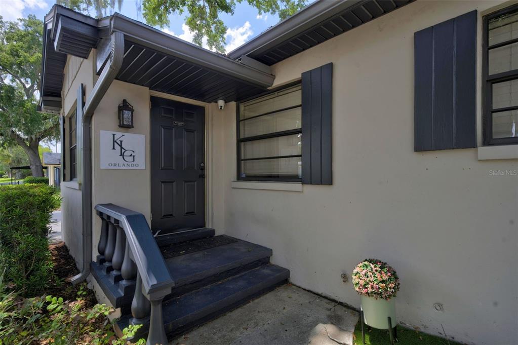 The exterior of a building features a dark door, steps, and a sign reading KG Orlando — 229 PASADENA PLACE, ORLANDO, FL