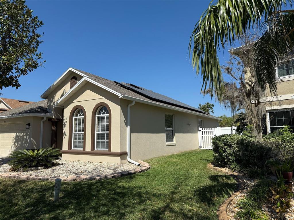 A tan single-story house with arched windows, a shingled roof, and solar panels — 2227 OAKINGTON STREET, WINTER GARDEN, FL