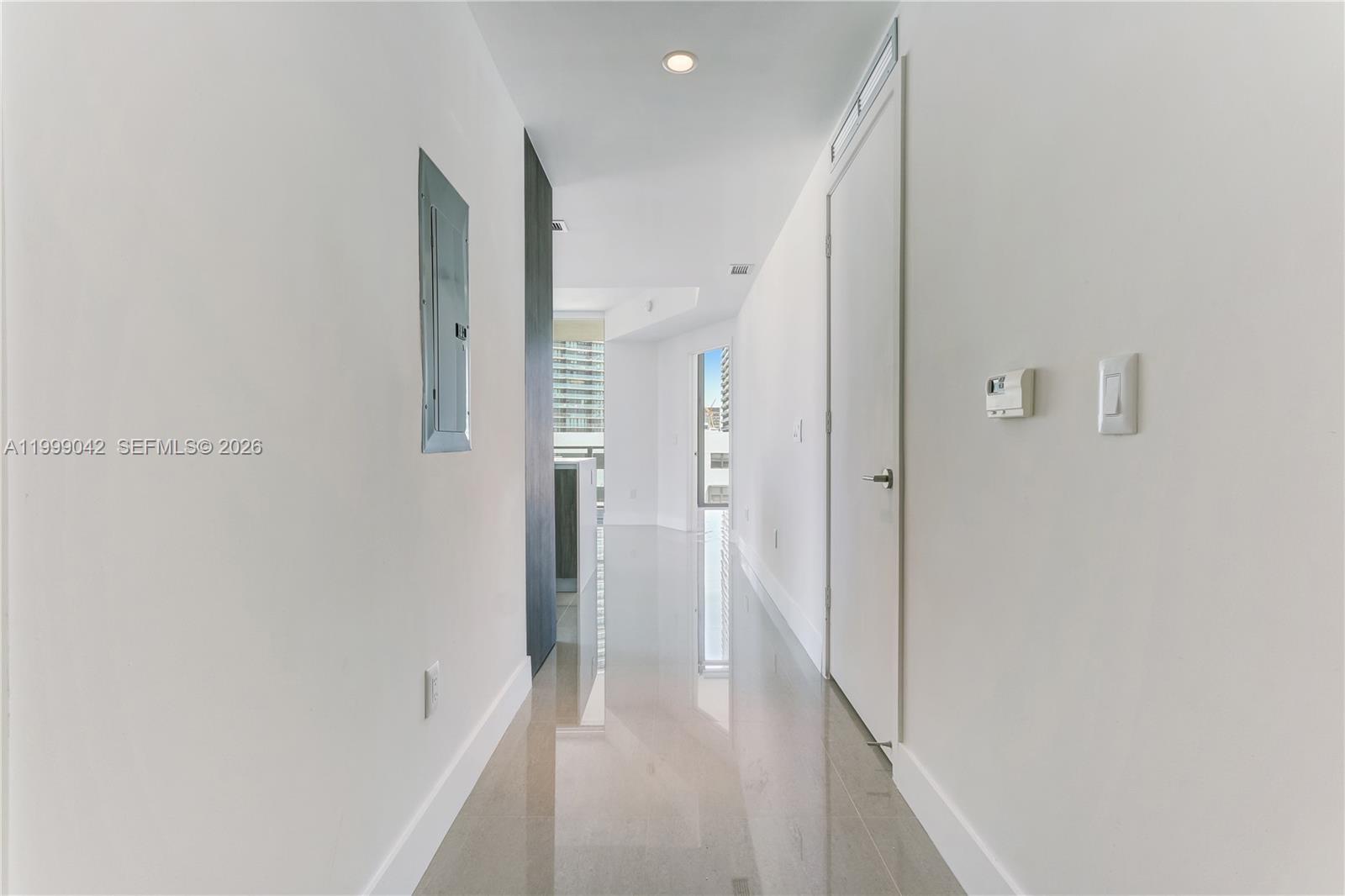 A bright hallway features white walls, glossy tile flooring, and a closed door — 2900 NE 7th Ave # 801, Miami FL 33137, MIAMI, FL