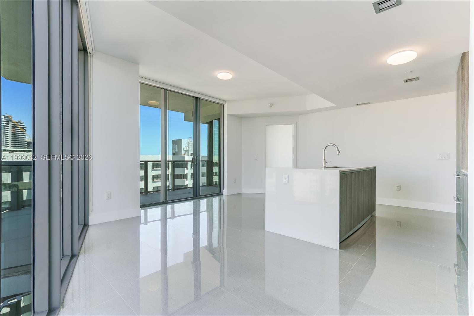 A modern kitchen with a white island and gray cabinetry opens to a balcony — 2900 NE 7th Ave # 801, Miami FL 33137, MIAMI, FL