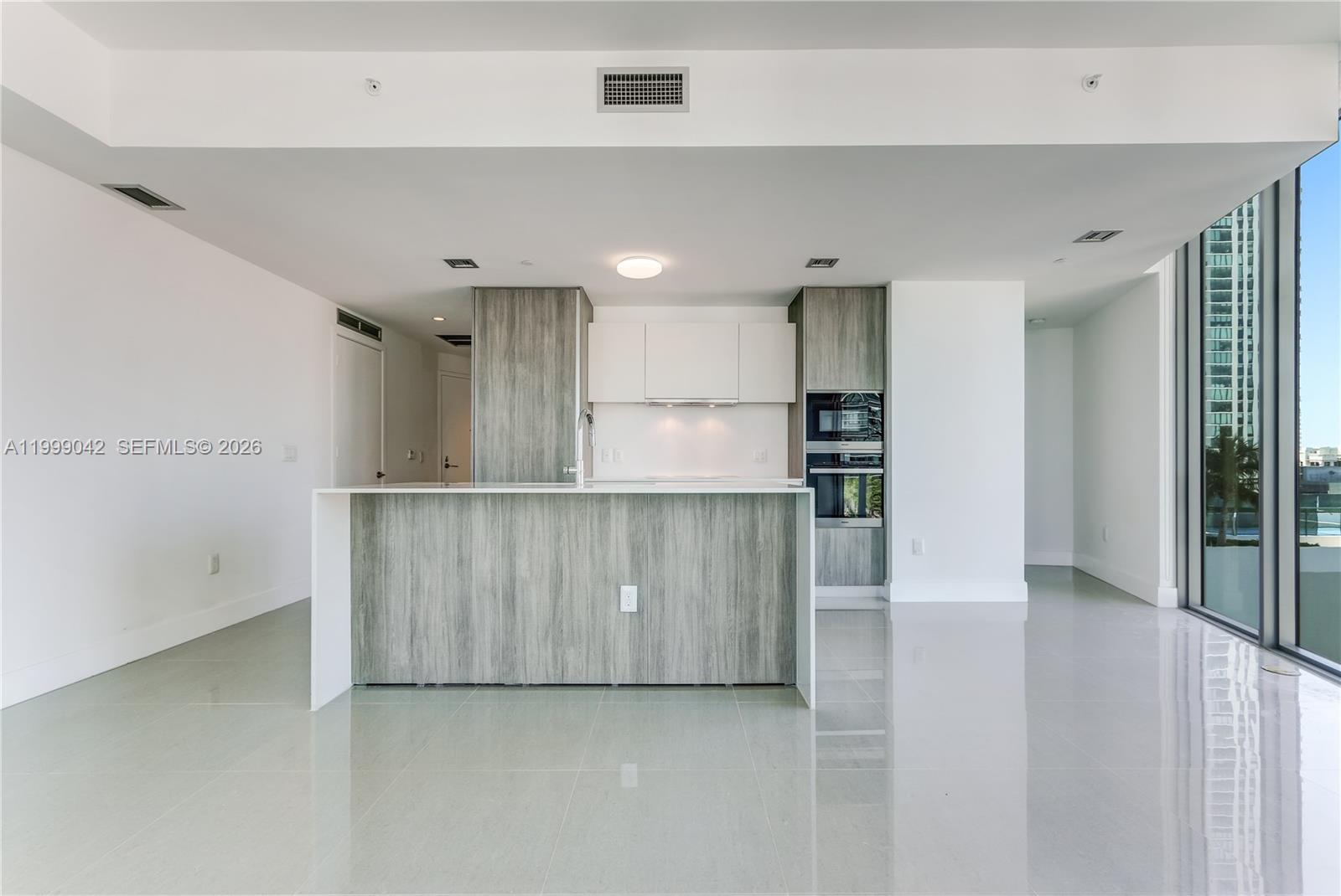 A modern kitchen features a wood-grain island, white cabinetry, and glossy tile flooring — 2900 NE 7th Ave # 801, Miami FL 33137, MIAMI, FL