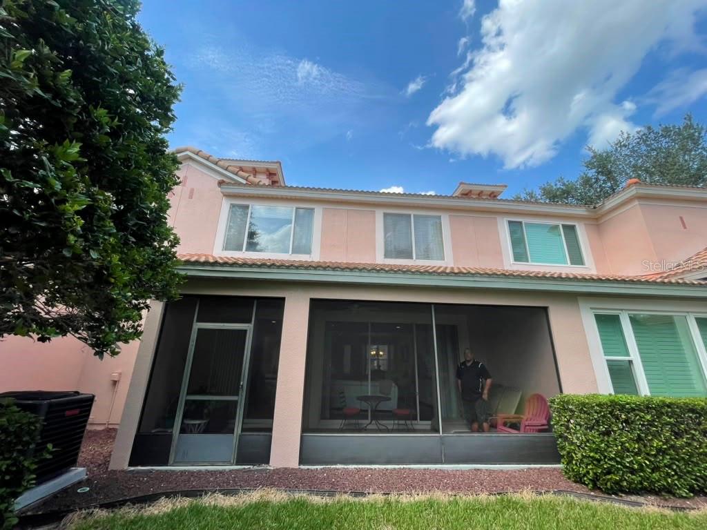 A two-story pink house with a screened-in patio and a grassy backyard — 1316 GILFORD POINT LANE, DAVENPORT, FL