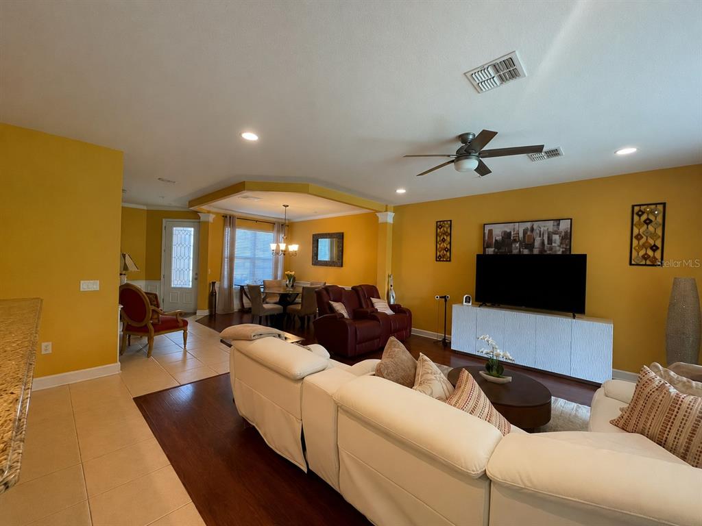 A living room and dining area with yellow walls, white furniture, and dark wood flooring — 1316 GILFORD POINT LANE, DAVENPORT, FL