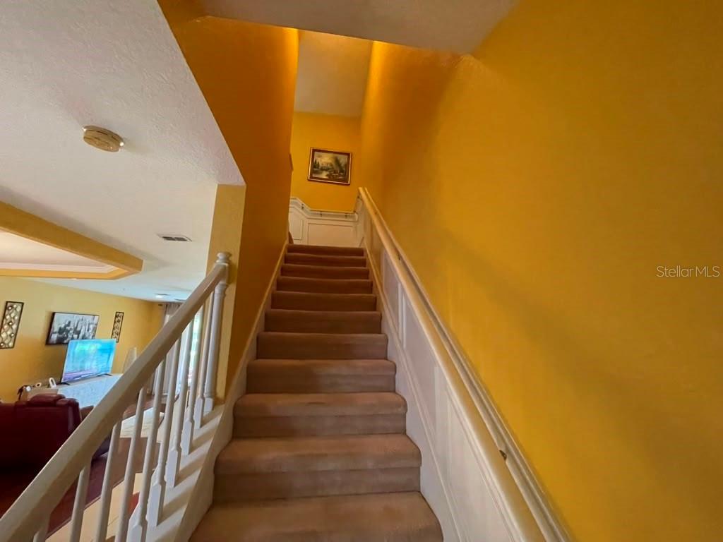 A carpeted staircase with white railings leads upward against bright yellow walls — 1316 GILFORD POINT LANE, DAVENPORT, FL