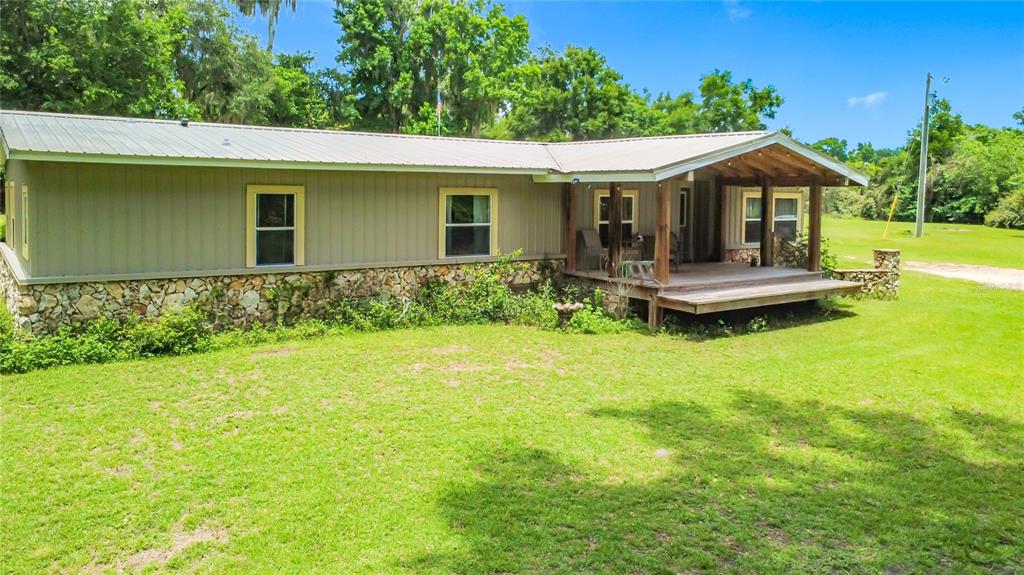 A single-story house with a metal roof, stone foundation, and a wooden front porch — 1919 NW 100TH STREET, OCALA, FL
