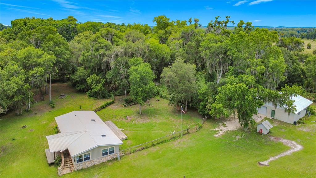 An aerial view shows a house with a metal roof, a detached garage, and trees — 1919 NW 100TH STREET, OCALA, FL