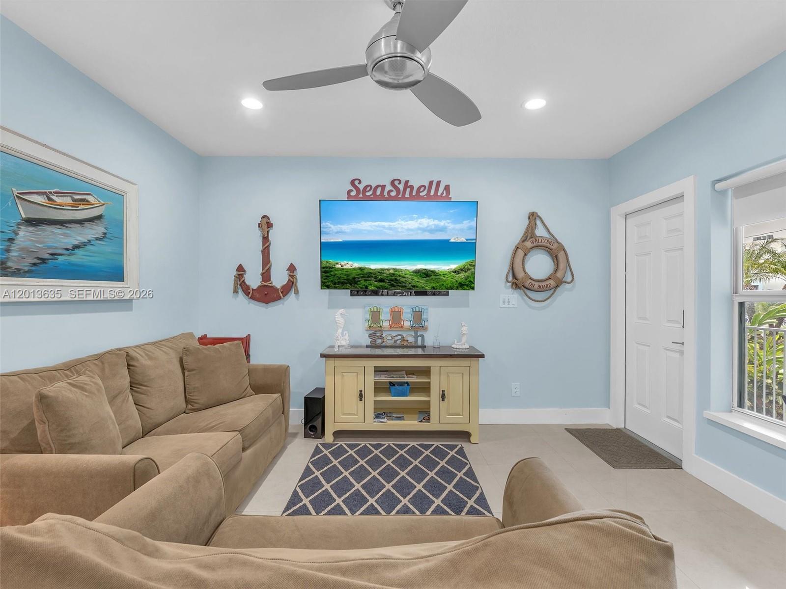 A living room features light blue walls, a tan sectional sofa, and beach-themed decor — 315 Van Buren St # 103B, Hollywood FL 33019, HOLLYWOOD, FL