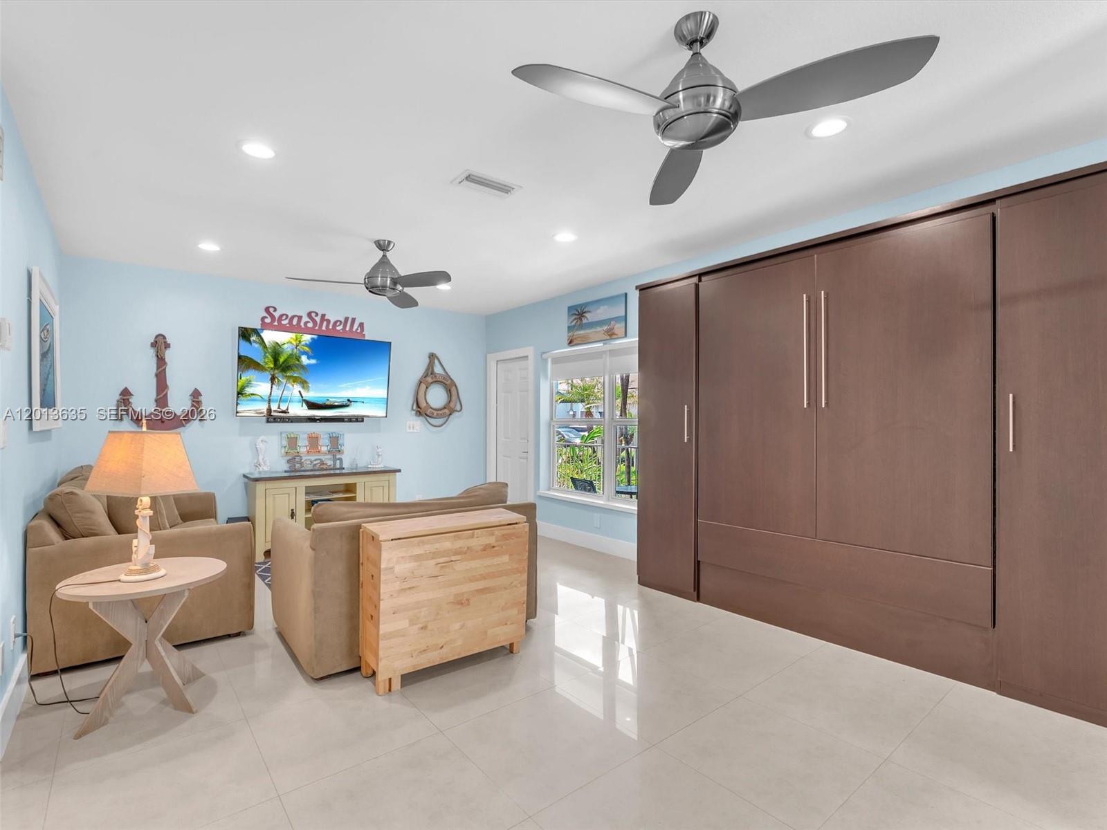 A living room features light blue walls, a large brown wall bed, and tile flooring — 315 Van Buren St # 103B, Hollywood FL 33019, HOLLYWOOD, FL