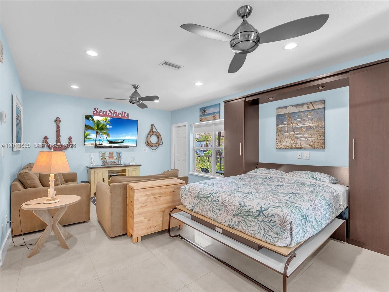 A bedroom features a pull-down Murphy bed, a seating area, and light blue walls — 315 Van Buren St # 103B, Hollywood FL 33019, HOLLYWOOD, FL