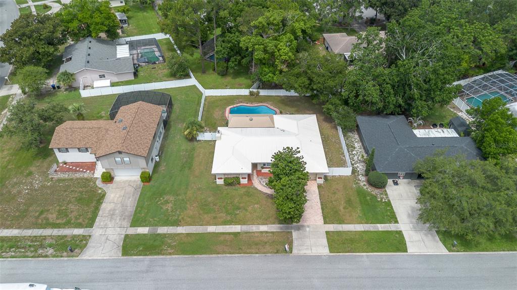 An aerial view shows three suburban houses with swimming pools and driveways along a street — 8208 TANSY DRIVE, ORLANDO, FL