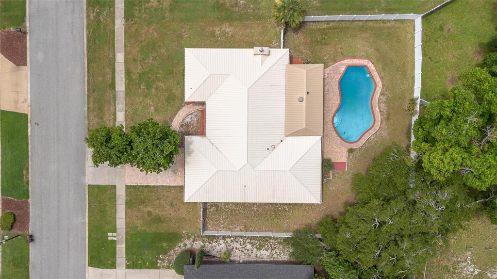 An aerial view shows a house with a metal roof, a pool, and a fenced yard — 8208 TANSY DRIVE, ORLANDO, FL
