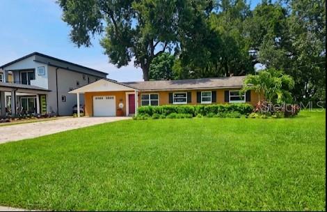 A single-story house with a yellow exterior, a white garage door, and a large lawn — 1903 SIMONTON AVENUE, ORLANDO, FL