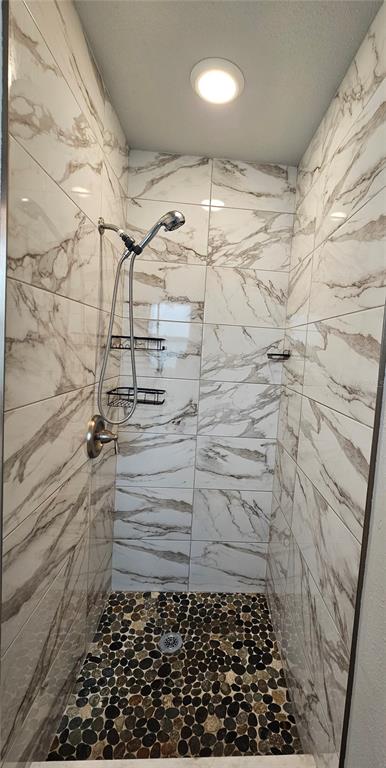 A walk-in shower features white marble-look wall tiles, a pebble floor, and a handheld showerhead — 1903 SIMONTON AVENUE, ORLANDO, FL