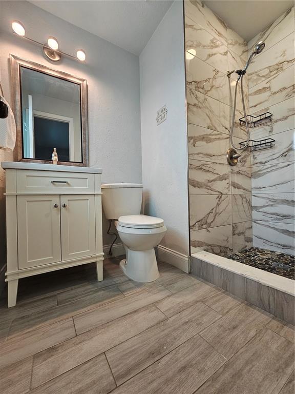 A bathroom features a vanity, toilet, and a walk-in shower with marble-look tile walls — 1903 SIMONTON AVENUE, ORLANDO, FL