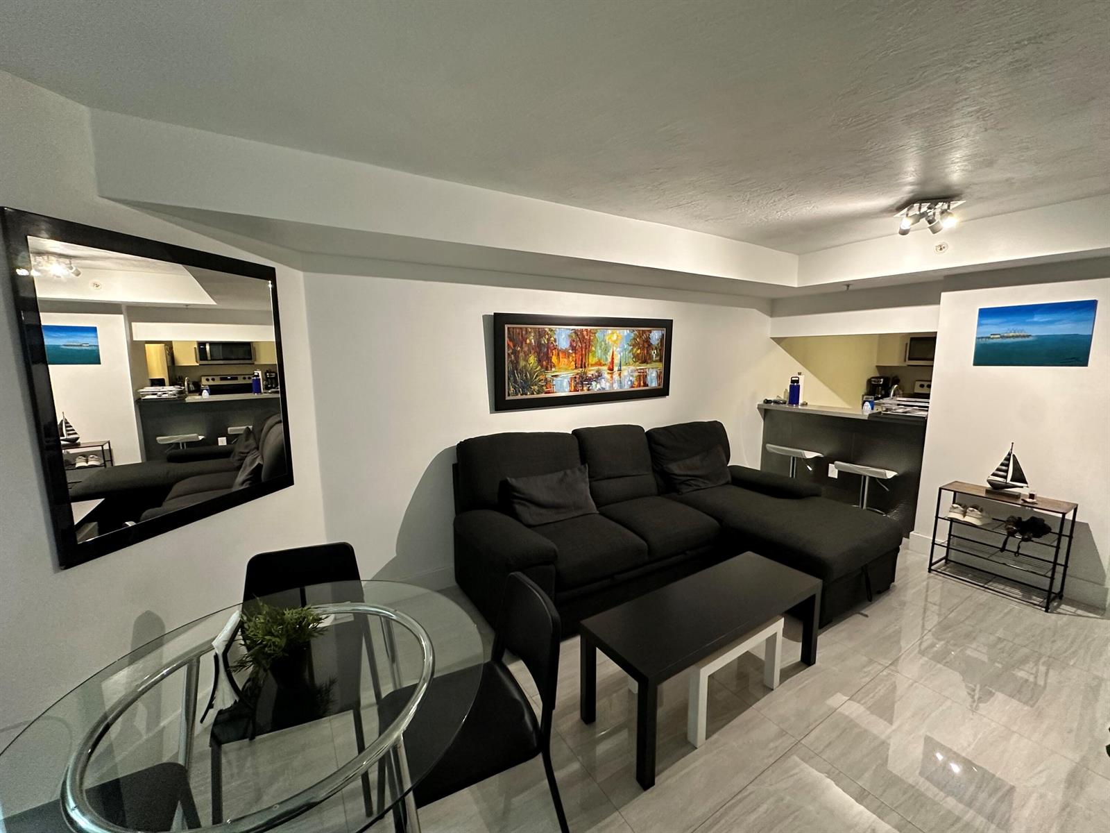 A living room with a black sectional sofa, glass dining table, and tiled flooring — 102 SW 6th Avenue # 206, Miami FL 33130, MIAMI, FL