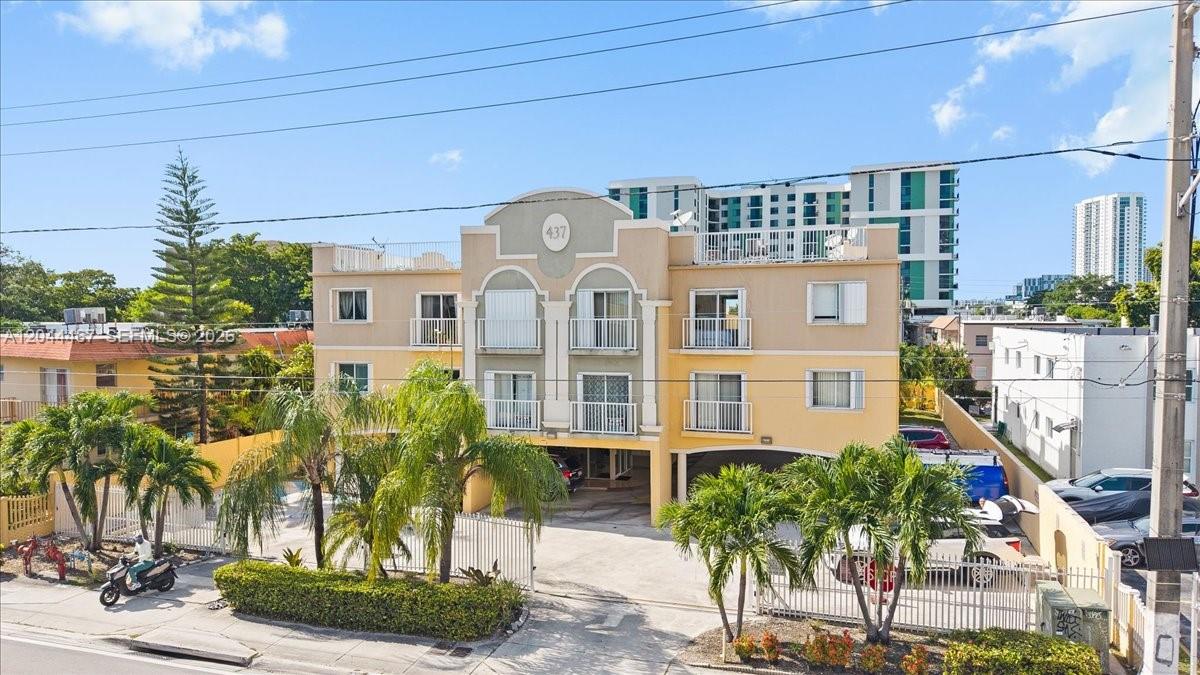 A three-story yellow apartment building with a ground-level parking area and palm trees — 437 SW 7th St # 201, Miami FL 33130, MIAMI, FL