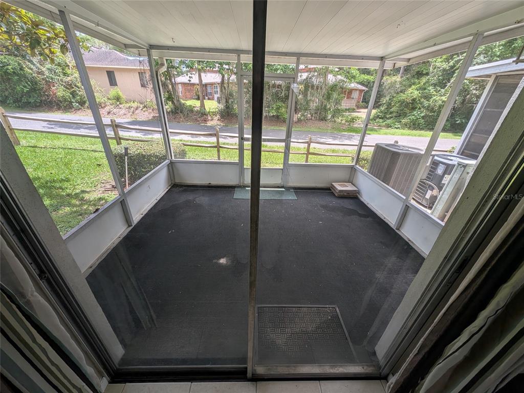A screened-in porch with a dark floor, sliding glass doors, and a view of the yard — 2524 SE 15TH AVENUE UNIT B, OCALA, FL