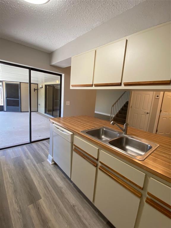 A kitchen features light-colored cabinets, a wood-look laminate countertop, a double sink, and vinyl flooring — 1004 ROYAL OAK BOULEVARD, LEESBURG, FL