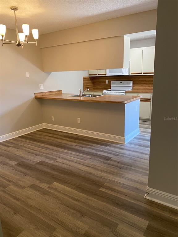 A dining area with wood-look flooring opens to a kitchen featuring a breakfast bar — 1004 ROYAL OAK BOULEVARD, LEESBURG, FL