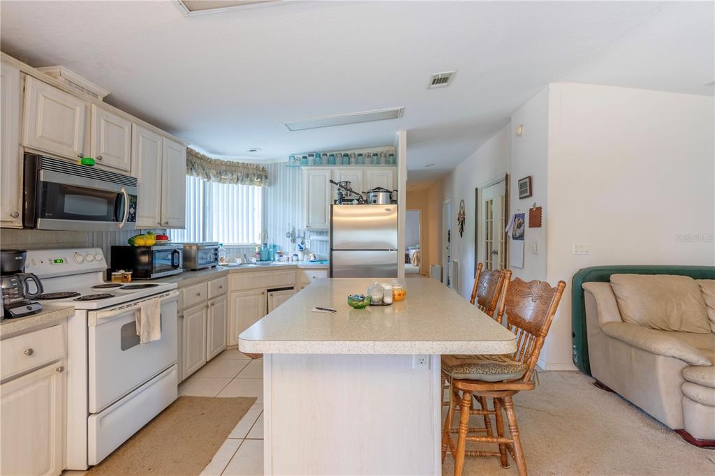 A kitchen features white cabinets, stainless steel appliances, a central island, and tile flooring — 2600 WACCASSA STREET, GENEVA, FL