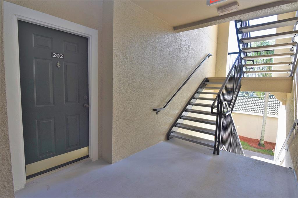 An exterior view of a apartment entrance door numbered 202 next to a metal staircase — 5122 NORTHRIDGE ROAD UNIT 202, SARASOTA, FL