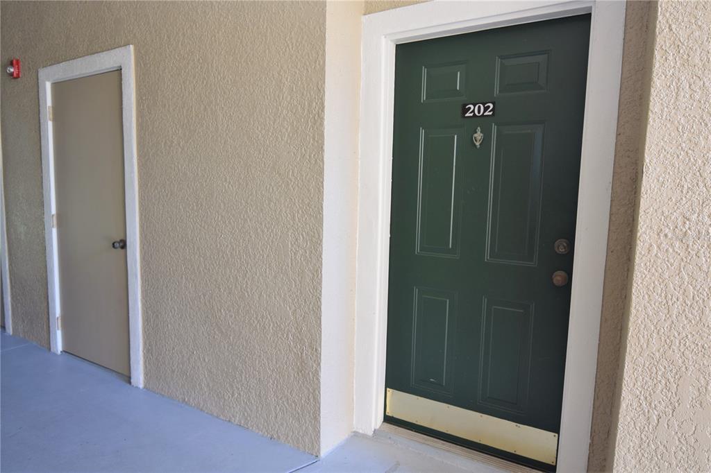 A green apartment door labeled 202 sits next to a plain beige door — 5122 NORTHRIDGE ROAD UNIT 202, SARASOTA, FL