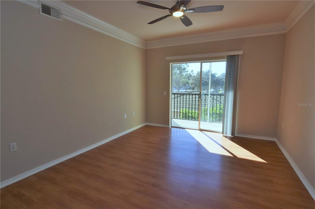 An empty bedroom features wood-look flooring, a ceiling fan, and a sliding glass balcony door — 5122 NORTHRIDGE ROAD UNIT 202, SARASOTA, FL