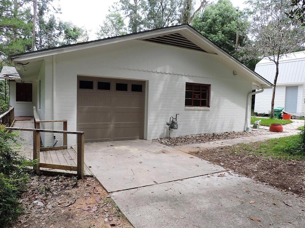 A white painted brick garage with a brown door and an adjacent wooden wheelchair ramp — 2049 NW 9TH AVENUE, GAINESVILLE, FL