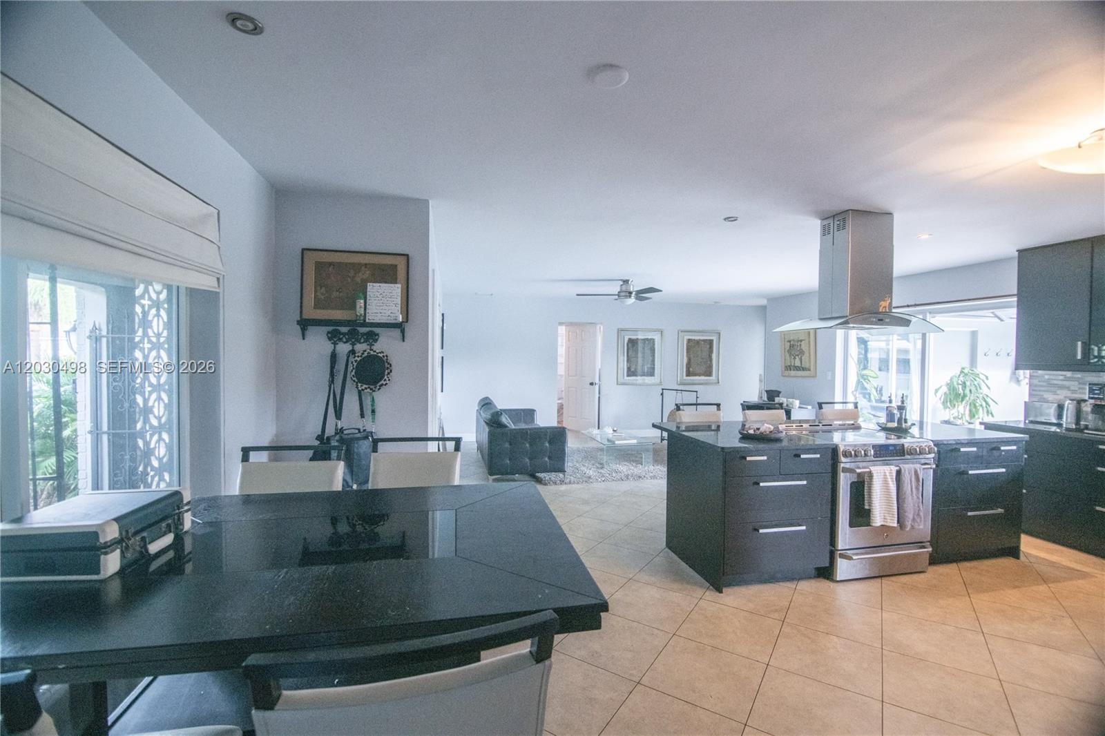 An open-concept kitchen and living area features dark cabinetry, a kitchen island, and tile flooring — 4116 Taft St, Hollywood FL 33021, HOLLYWOOD, FL